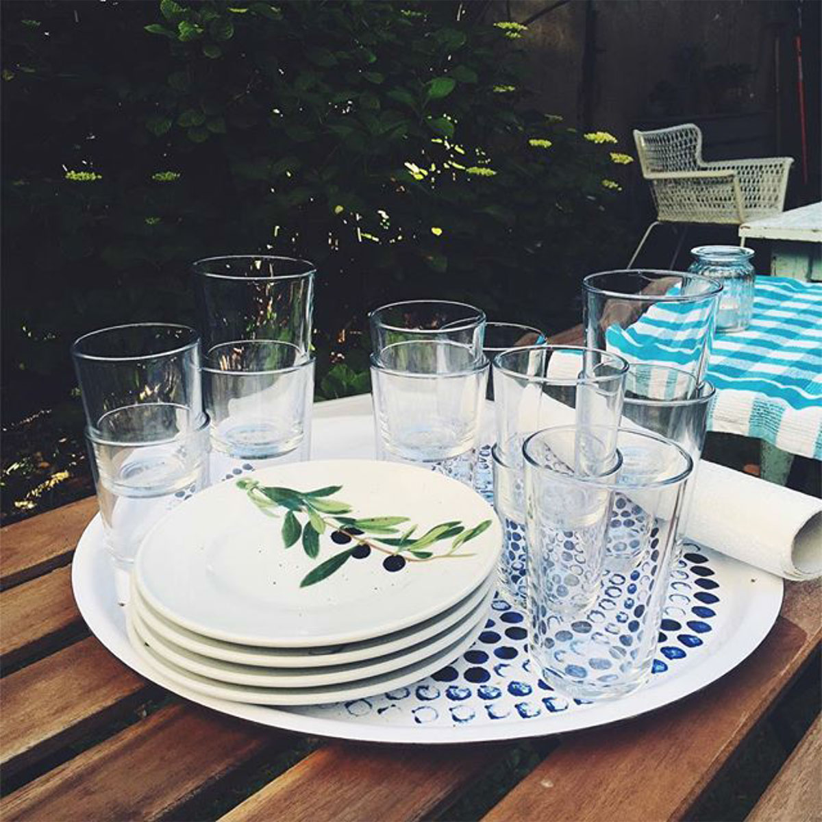 Teller und Gläser auf einem Tablett auf einem Gartentisch