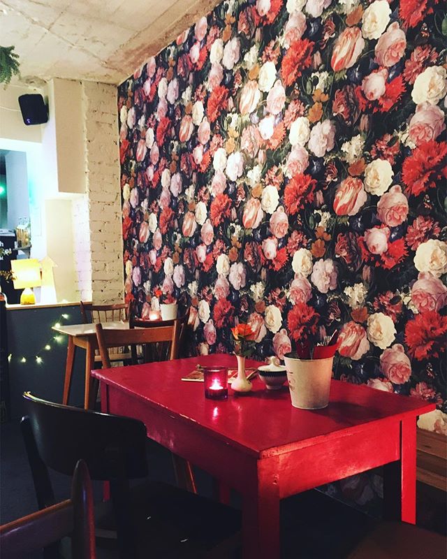 Foto ein roter Tisch steht vor einer mit Blumenmuster tapezierten Wand