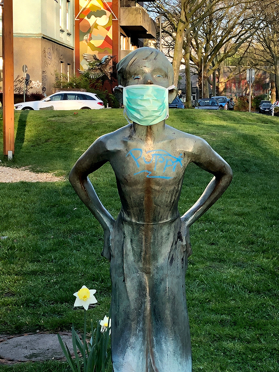 Eine weibliche Bronzestatue in einem Park trägt einen Mundschutz – Corona 2020