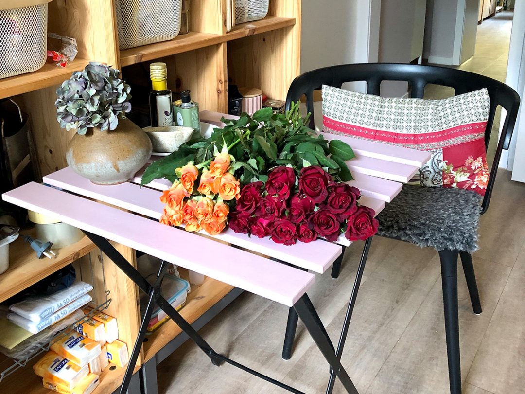 Zwei verschiedene Rosensträuße liegen auf einem Tisch in einer Küche