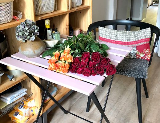 Zwei verschiedene Rosensträuße liegen auf einem Tisch in einer Küche