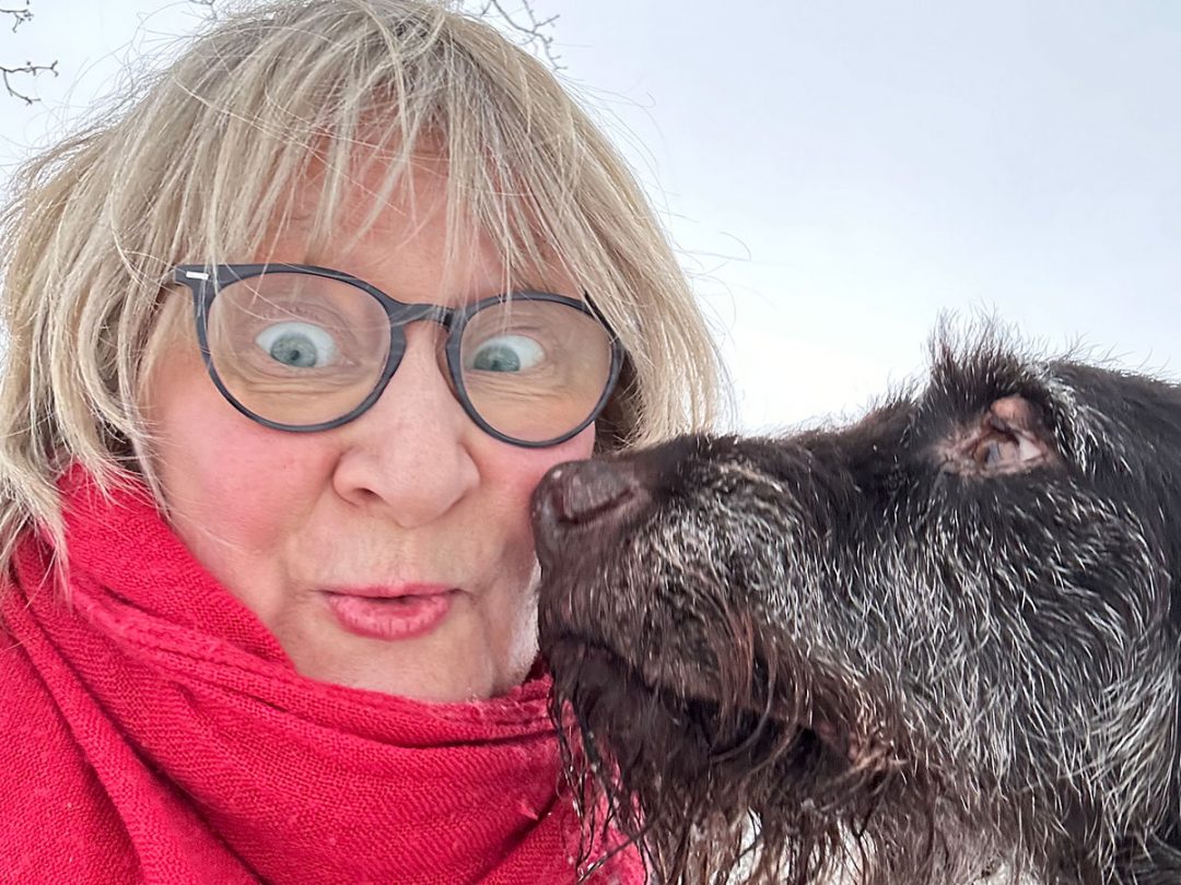 Eine Frau mit Brille und einem roten Schal und ein Deutsch-Drahthaar-Hund