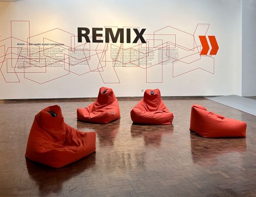 Ein Szene aus einem Museum rote Knautschsessel vor einer Wand mit abstraktem Muster und dem Schriftzug "Remix"